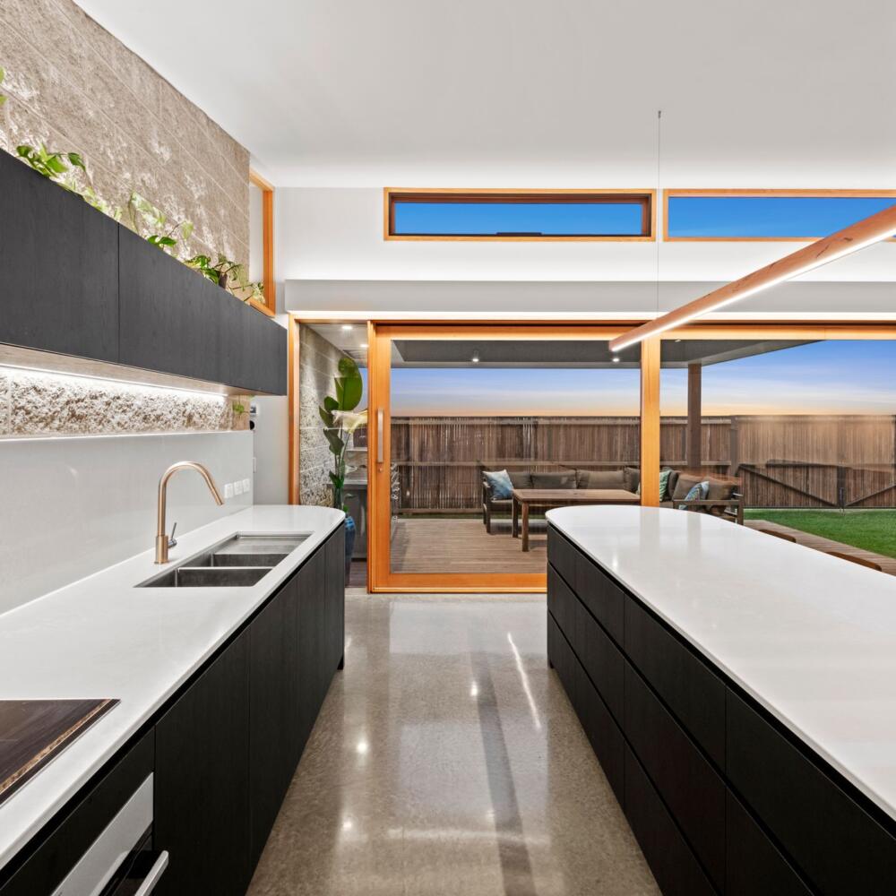Looking through a kitchen to outside living are via large glass timber sliding doors