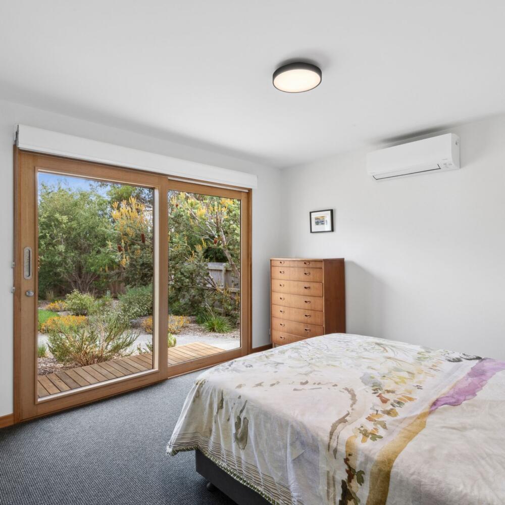 A bedroom with beautiful sunlight coming through double glass sliding doors